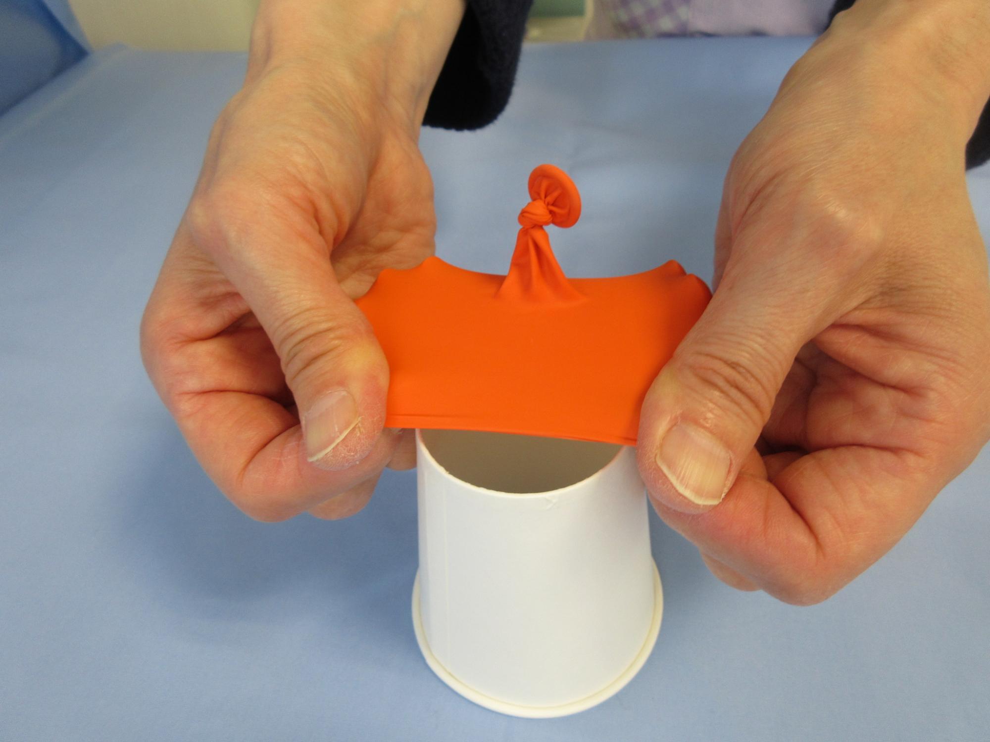 オレンジ色のゴムを紙コップに被せている写真