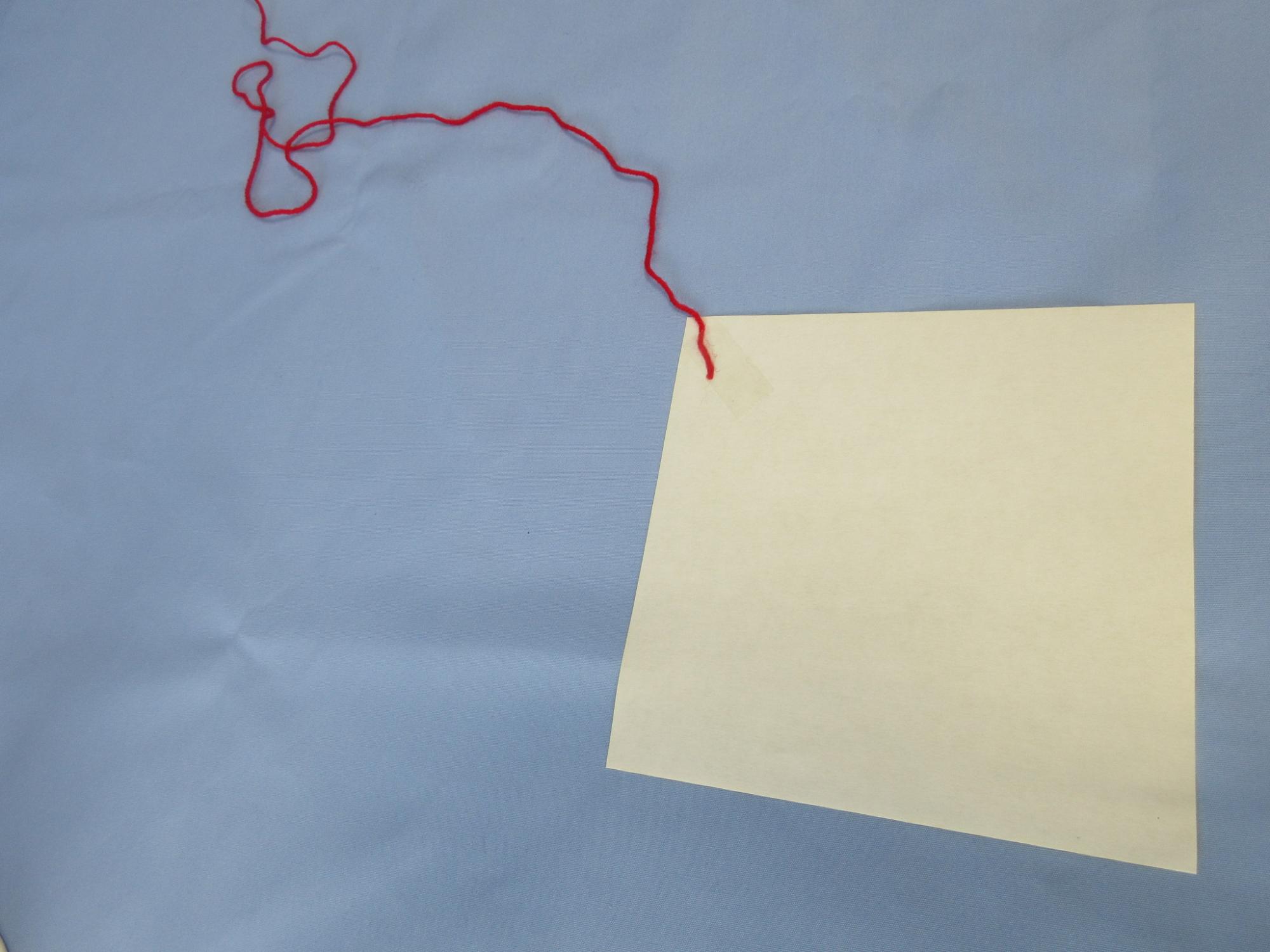 白い紙と赤いひもが並べられている写真