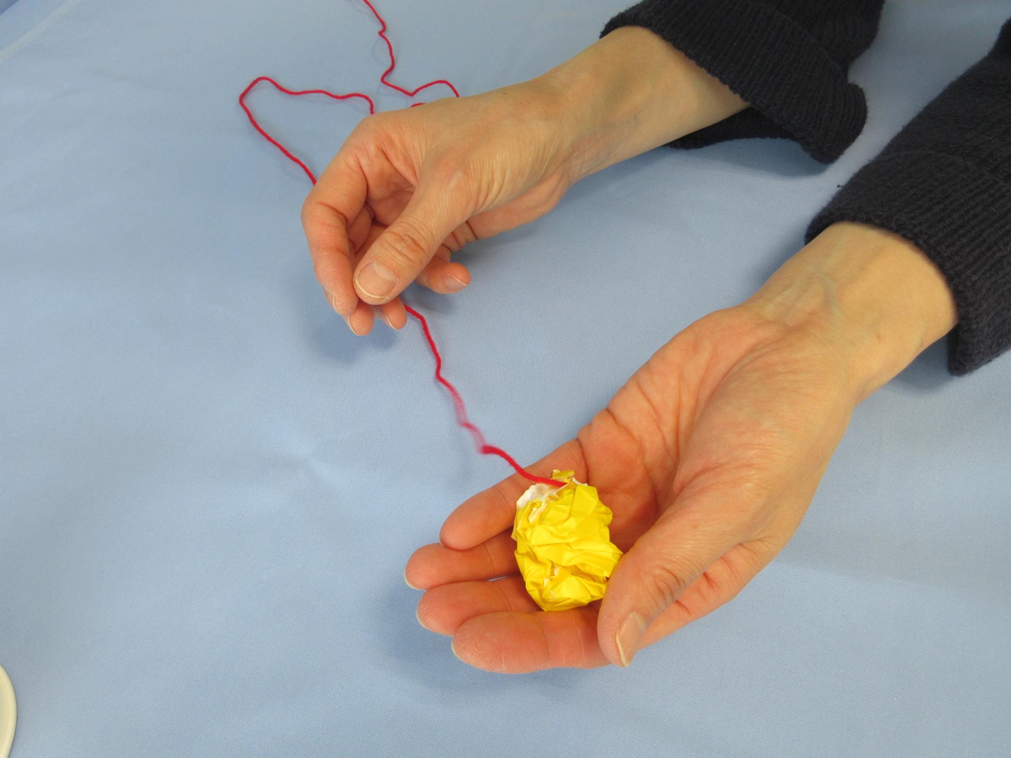 手のひらに丸められた黄色い紙が乗っている写真