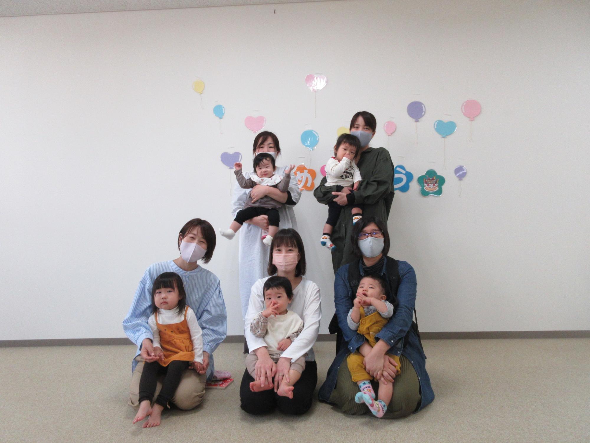 後ろに2組立ち、前に3組座る母子の写真