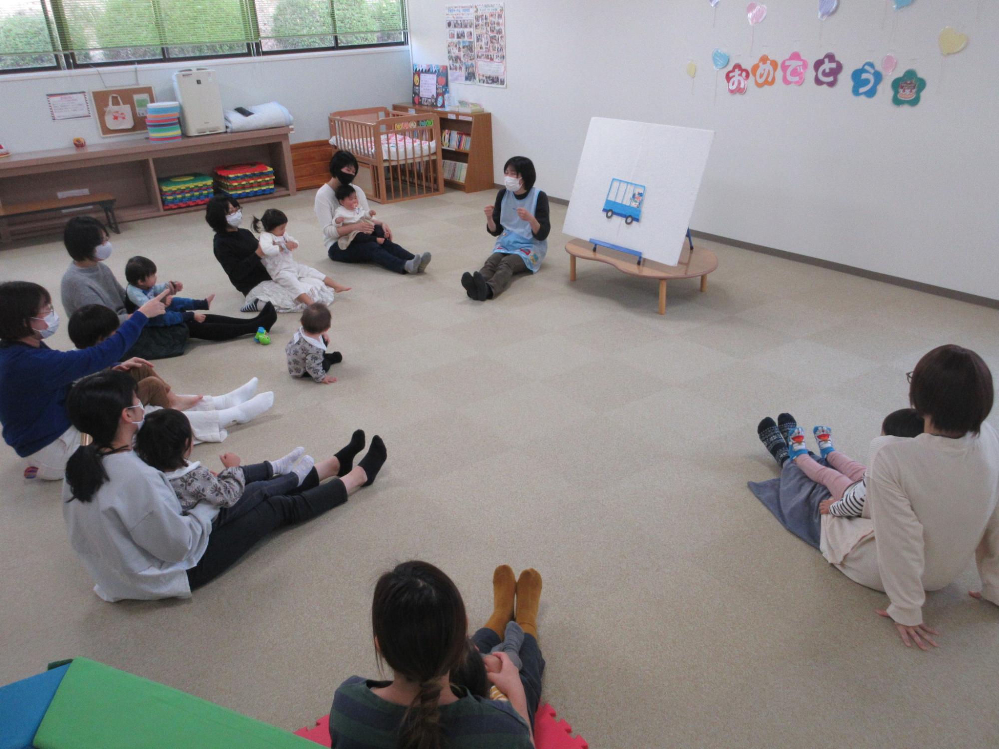 親子が座ってパネルのイラストを見ている写真