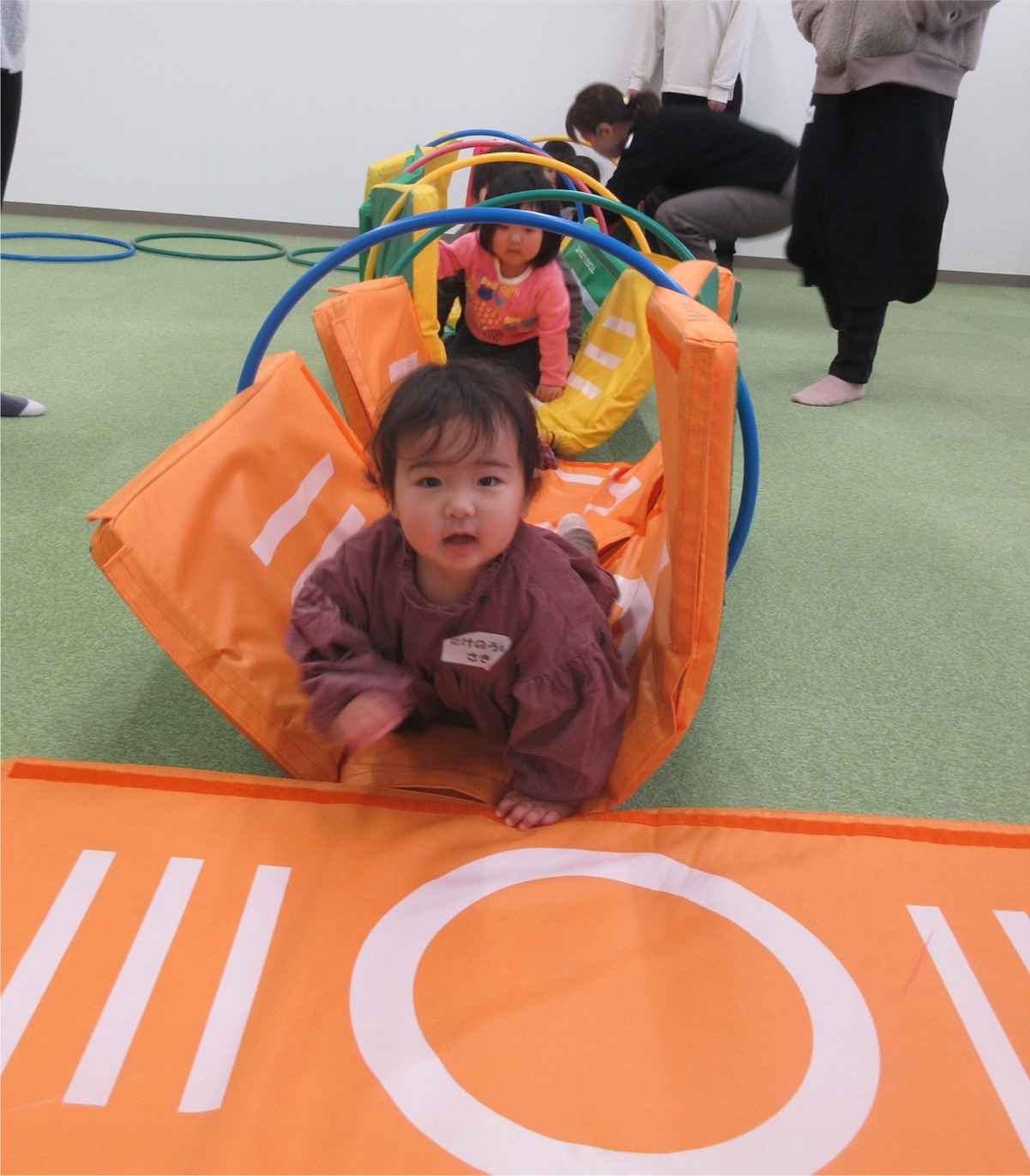 トンネル型の遊具をくぐる子供たちの写真