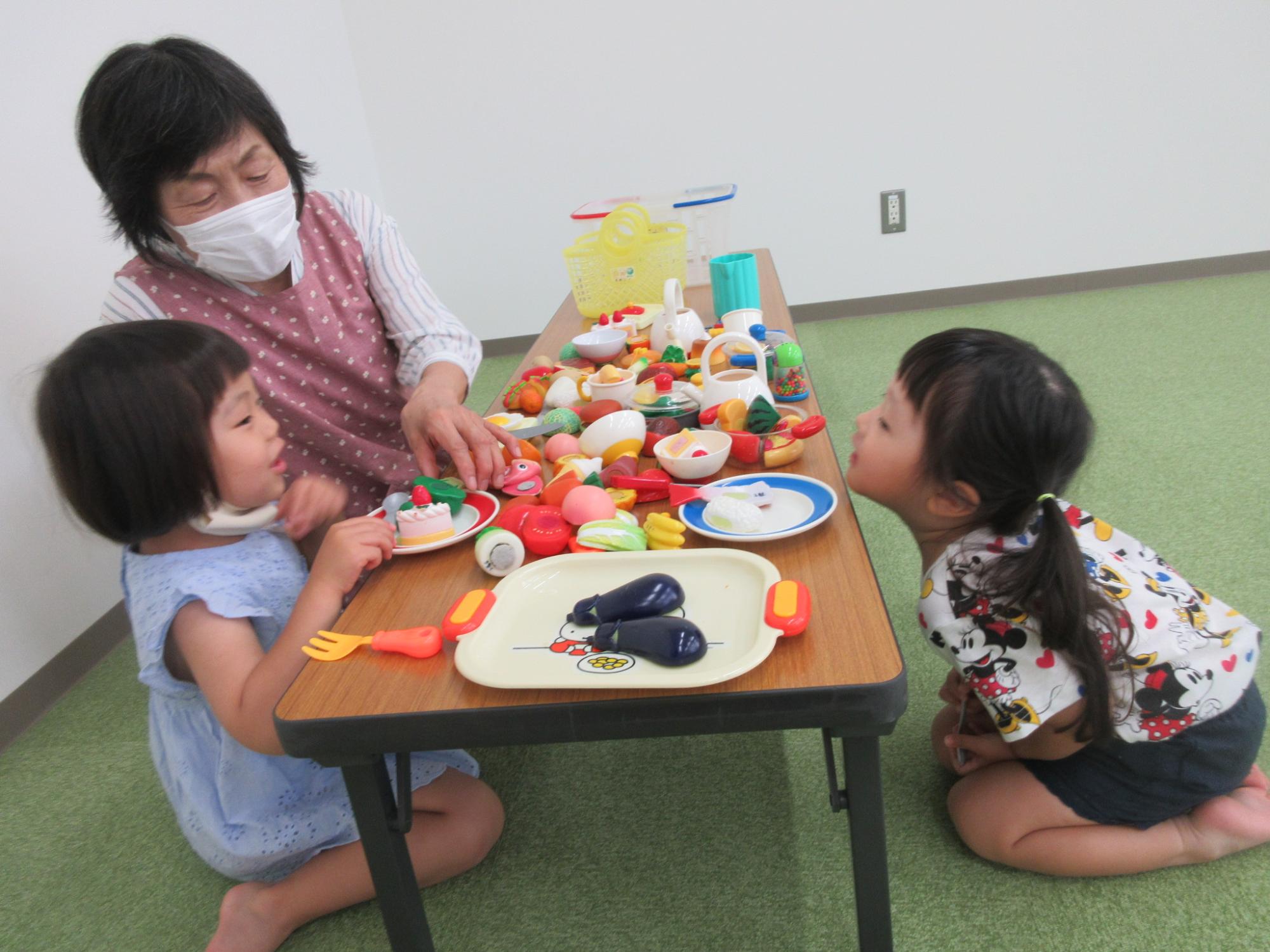 おままごとで遊ぶ女性と子供2人の写真