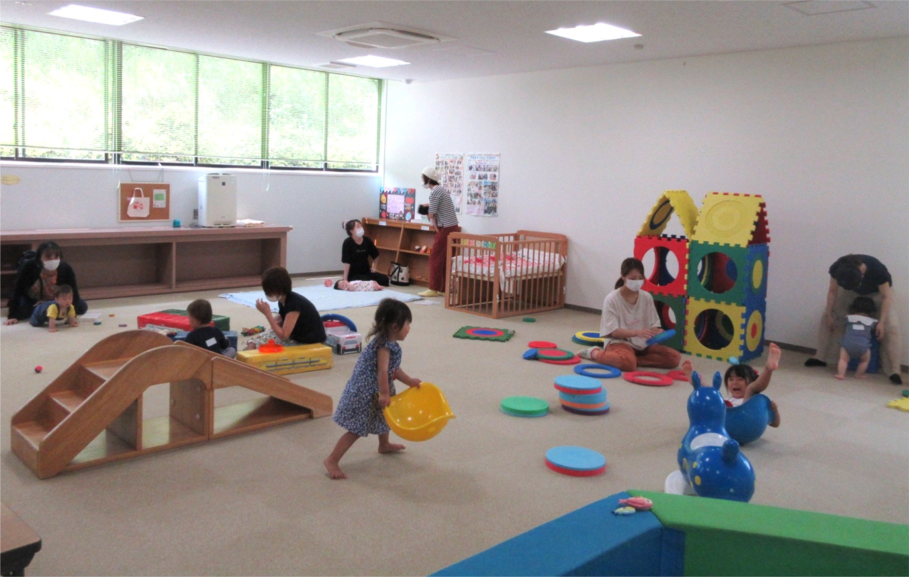 遊具が置かれた部屋で遊ぶ子供達の写真