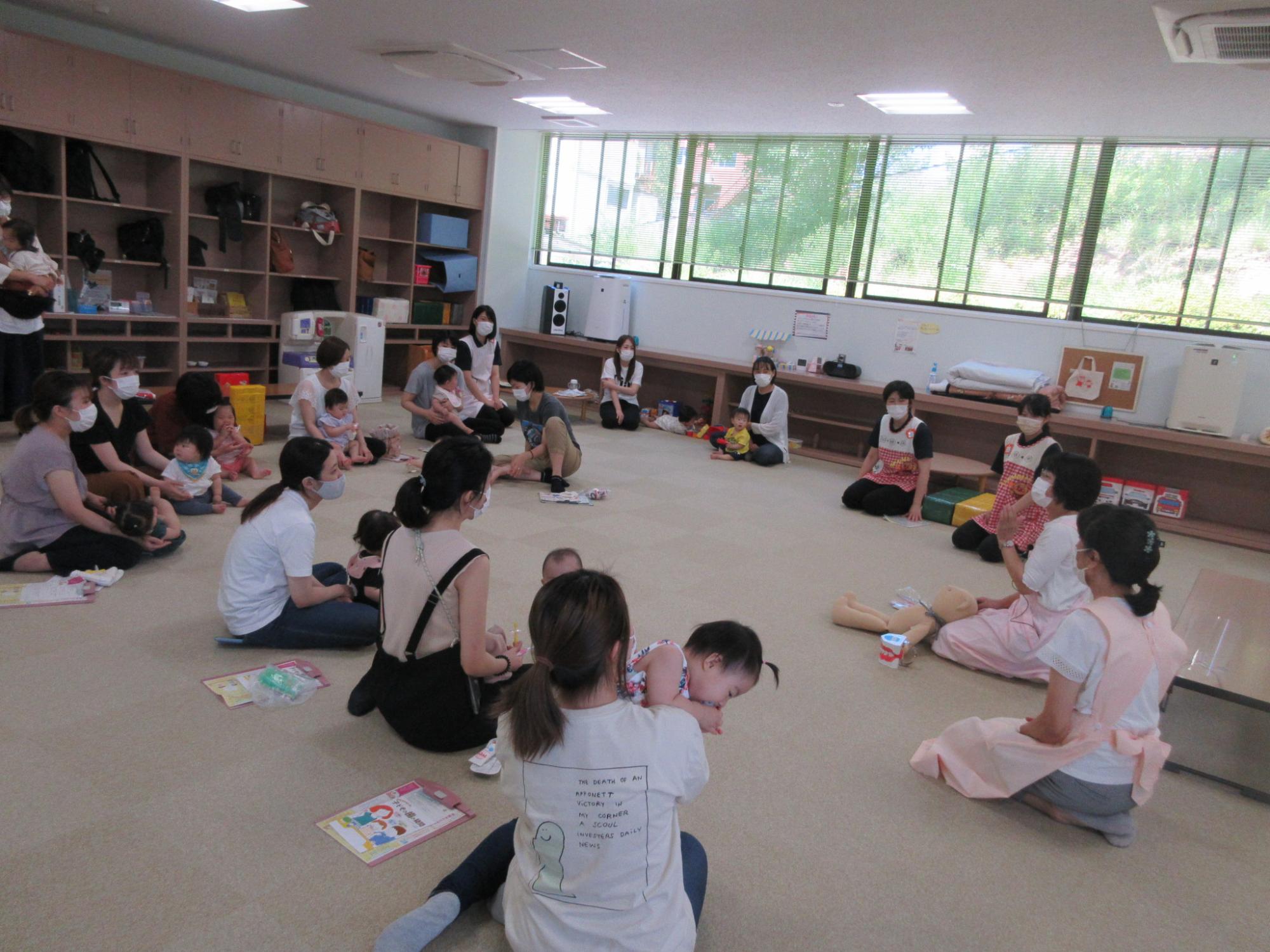 輪になって座った保護者達が女性の話を聞いている写真