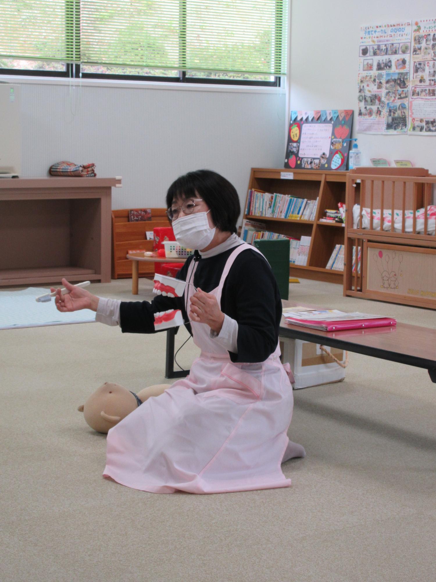 歯の模型を持ちながら座って話す女性の写真