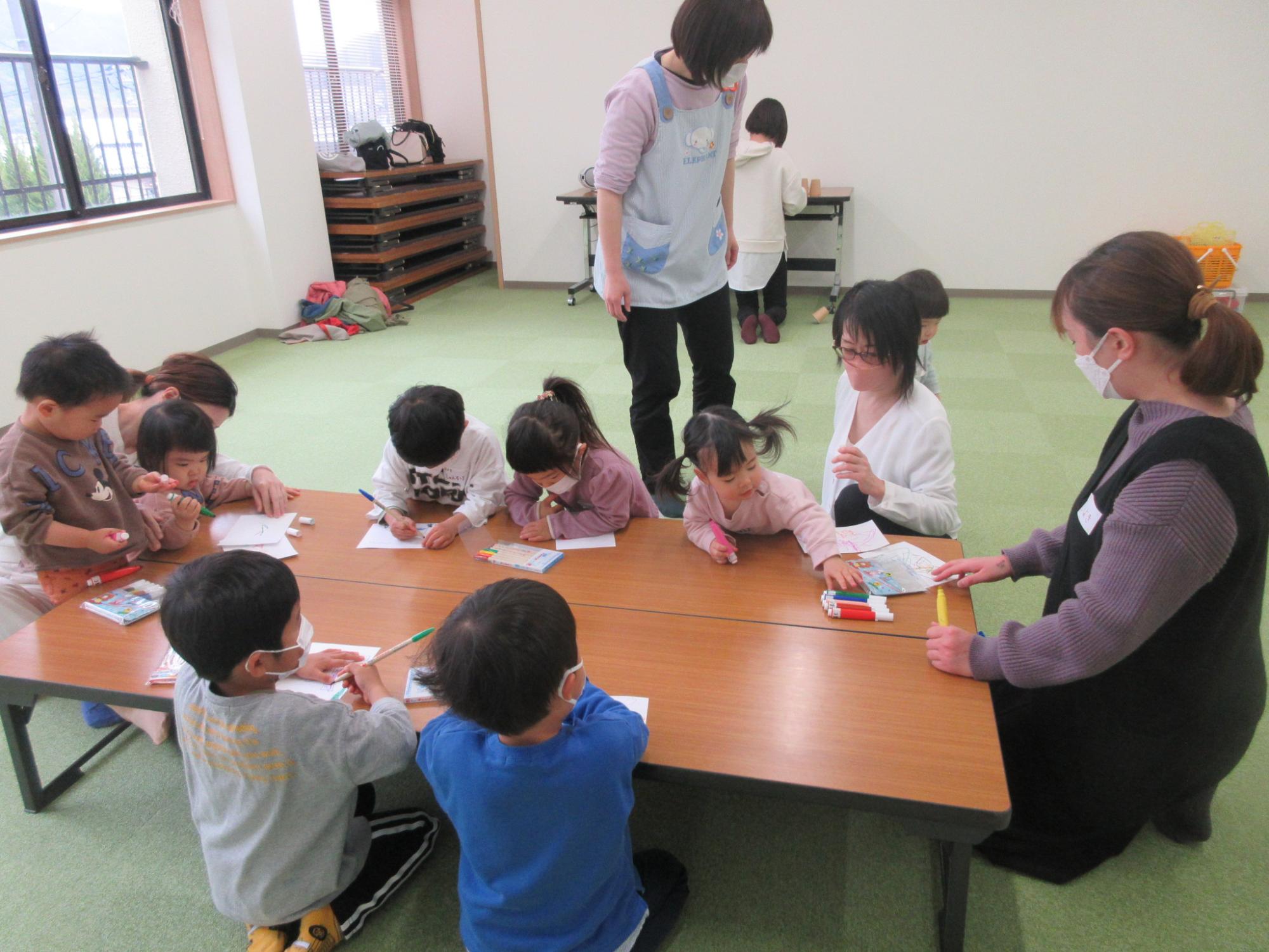 机で絵を描く子供達の写真