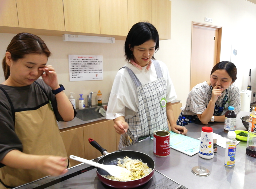エプロンをかけた女性たちが調理をしている写真
