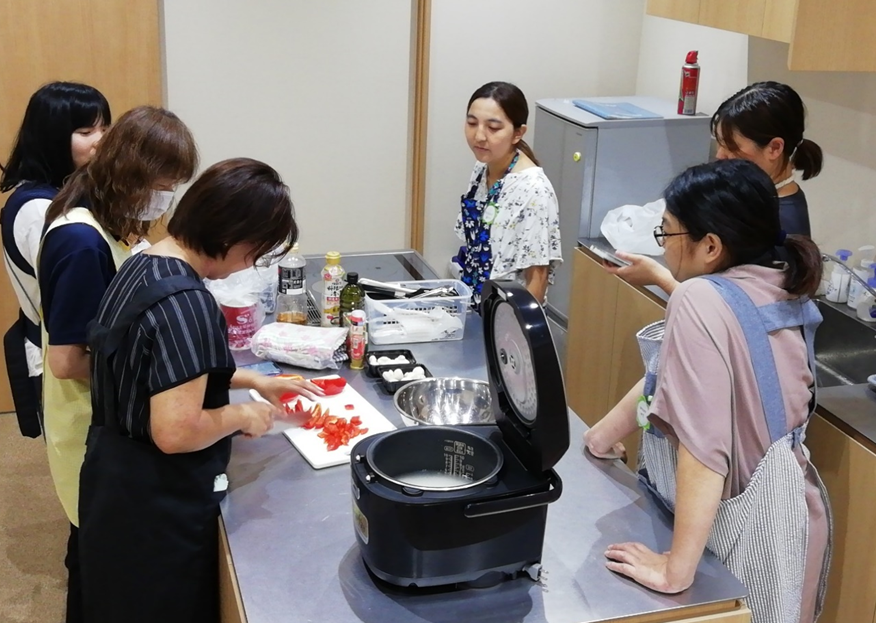 調理台に集まった女性たちが料理をしている写真