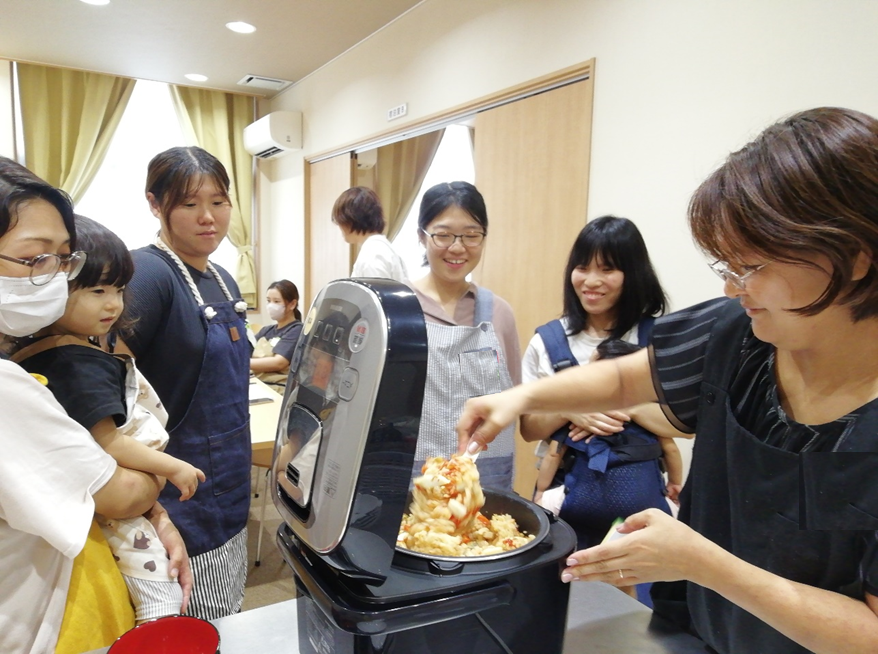 炊飯器のご飯をかき混ぜている女性の写真