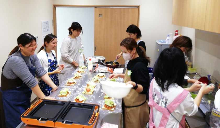 ホットプレートが置かれた調理台で盛付をしている女性たちの写真