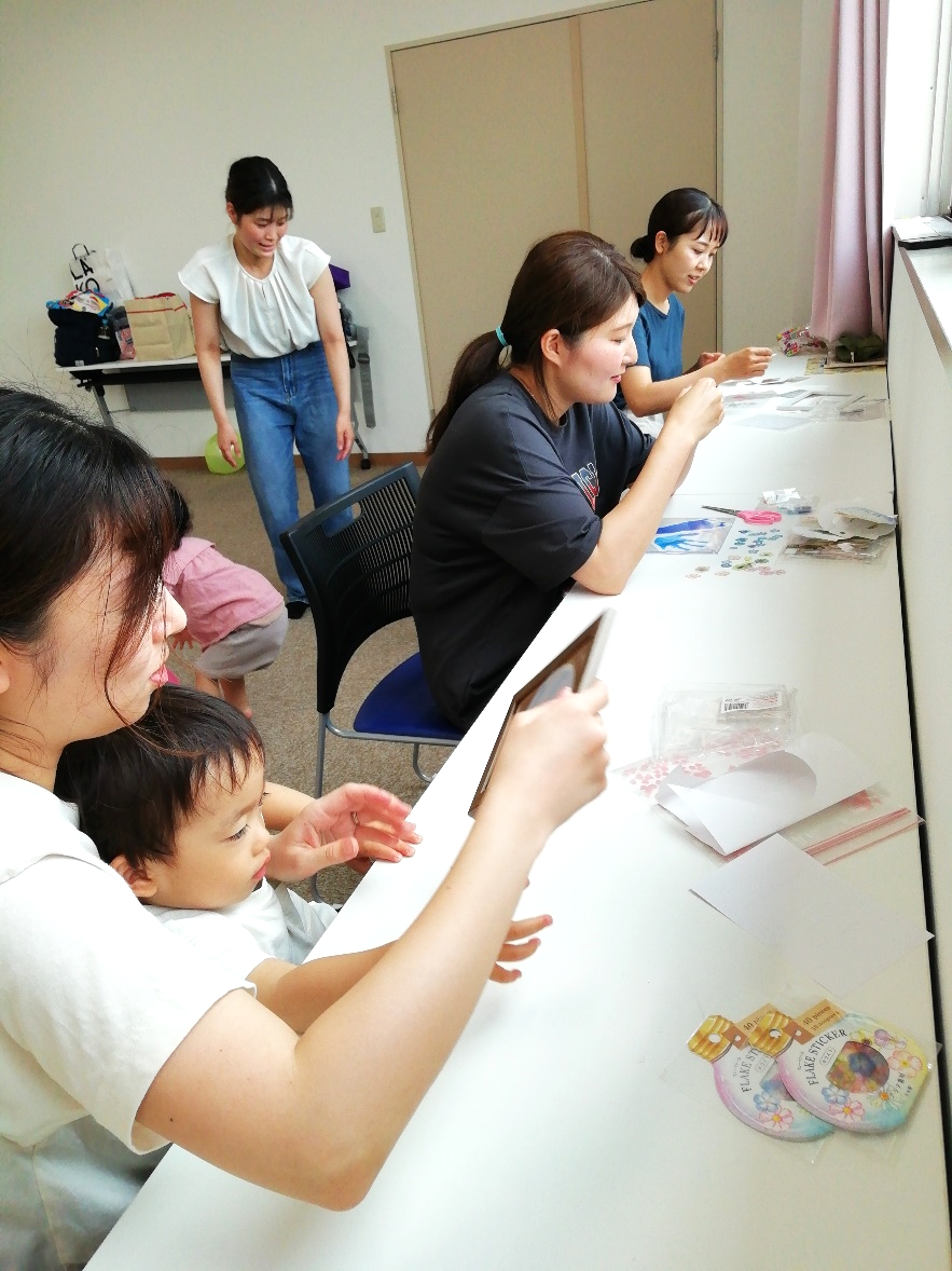窓際のテーブルで工作をしている親子たちの写真