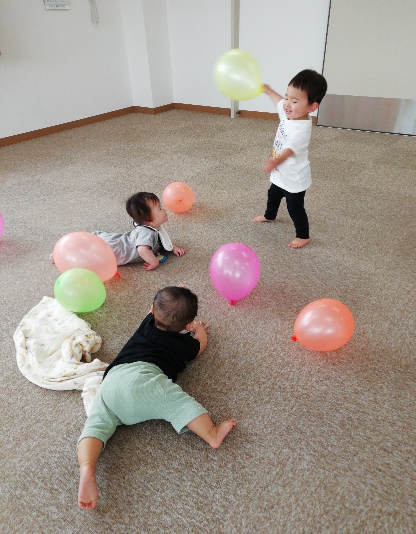 床に置かれた風船で遊んでいる子供たちの写真