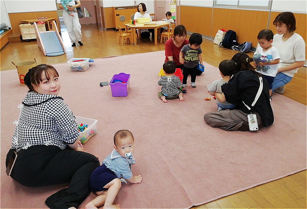 カーペットの敷かれた室内で遊ぶ親子たちの写真