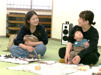 2人の女性の片方が膝に赤ちゃんを座らせながらお互いに話をしている写真