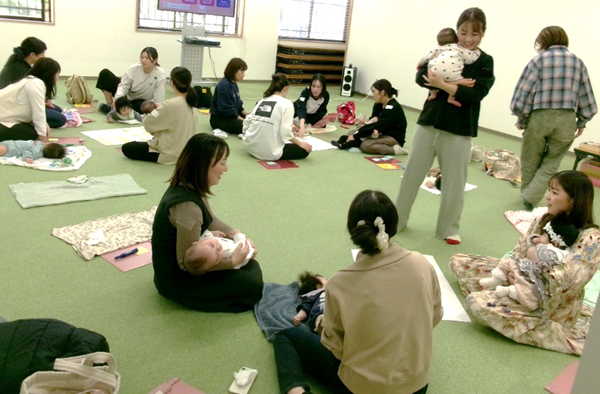 たくさんの女性たちが赤ちゃんをだっこしながら話をしている写真