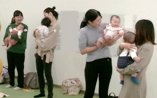 4人の女性たちが赤ちゃんをだっこしながら笑い合っている写真