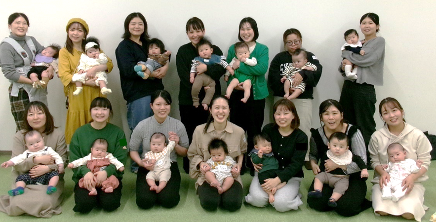 たくさんの女性たちが赤ちゃんを抱っこしながら並んで笑っている写真