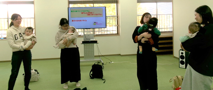 女性たちが赤ちゃんを腕に抱いて立っている写真