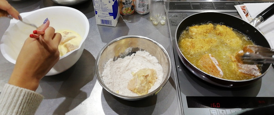 衣をつけたチキンを揚げている写真