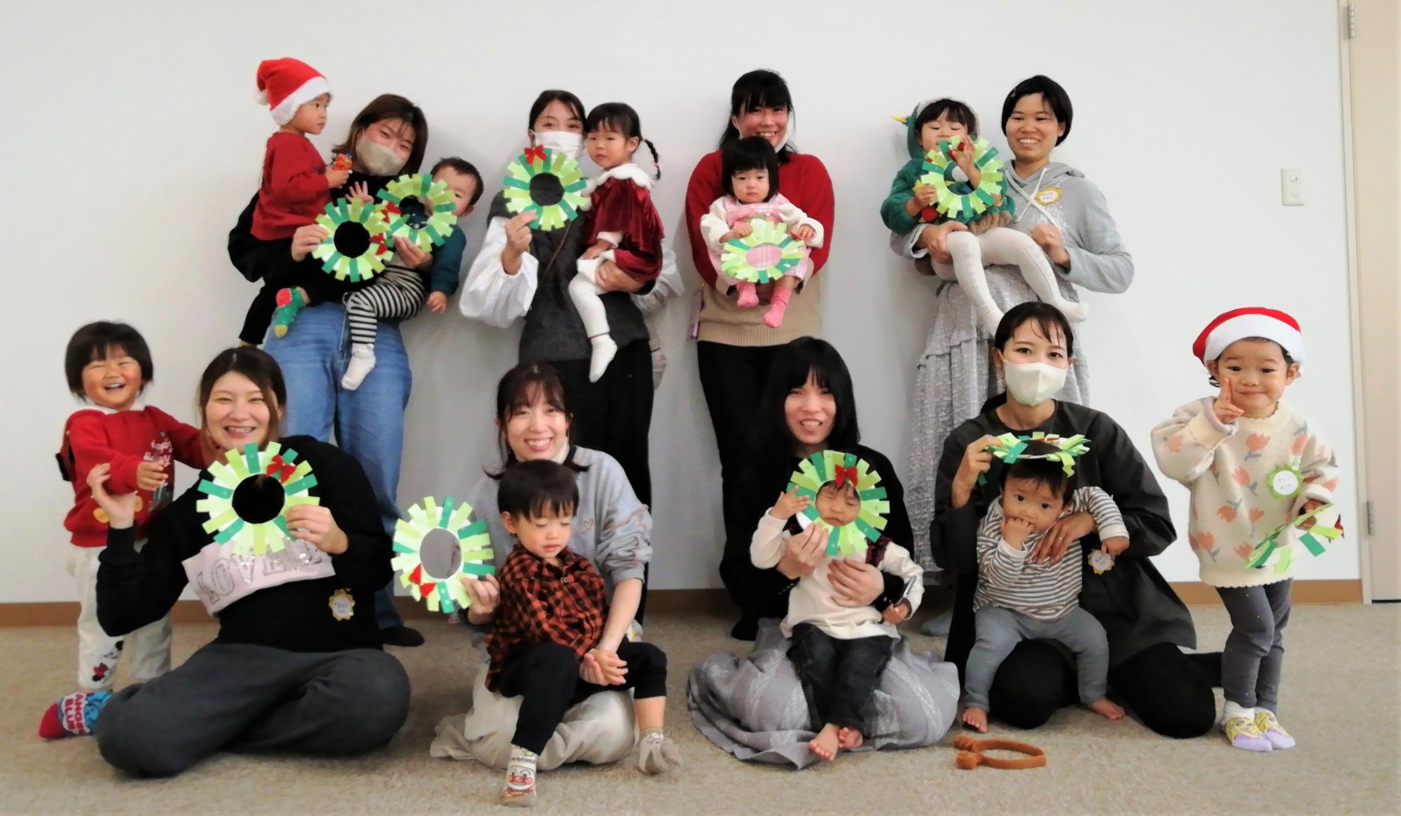 手づくりのクリスマスリースを持って並んでいる親子たちの写真