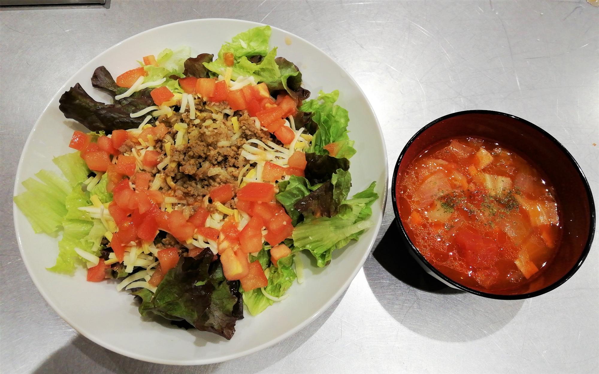 タコライスが盛りつけられたお皿とミネストローネが入れられたお椀が並べられている写真