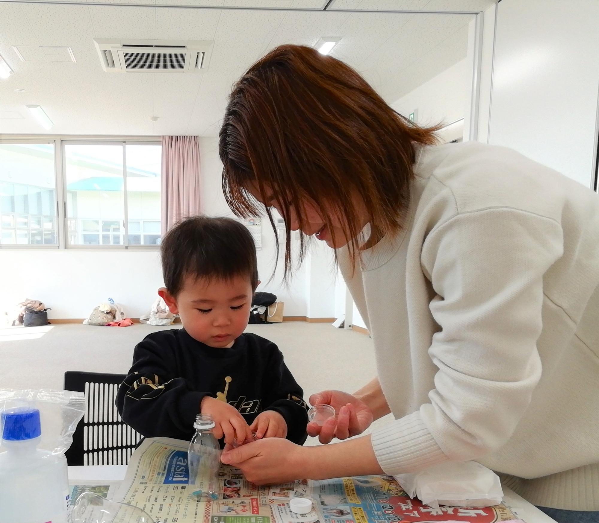 ペットボトルの工作をしている親子の写真