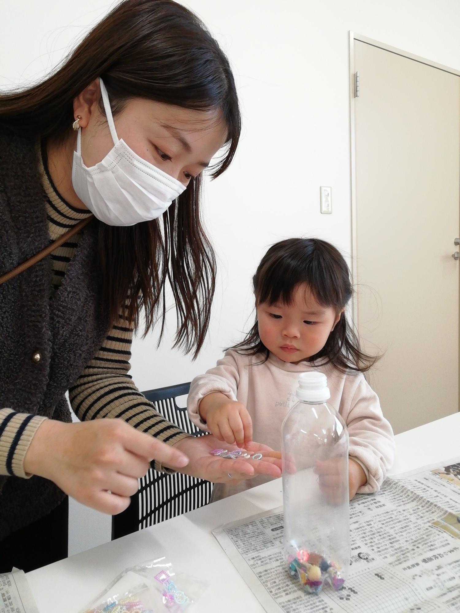 ペットボトルにアクセサリーを入れている親子の写真