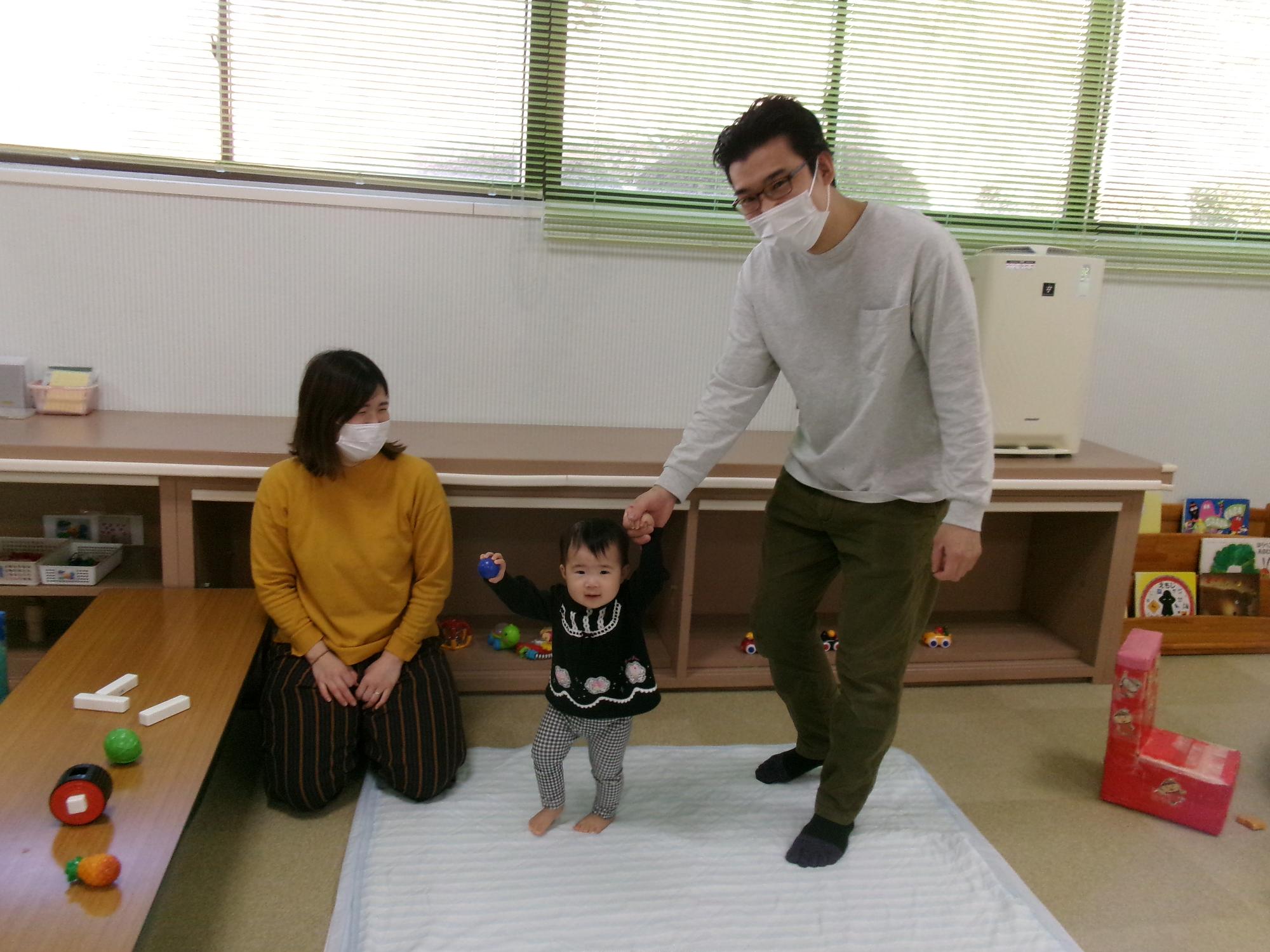 子どもと手を繋いでいるお父さんと見守るお母さん