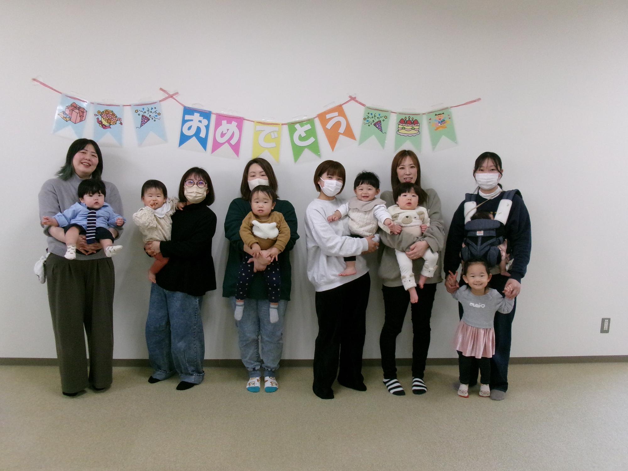 誕生会で集合写真をとっている親子