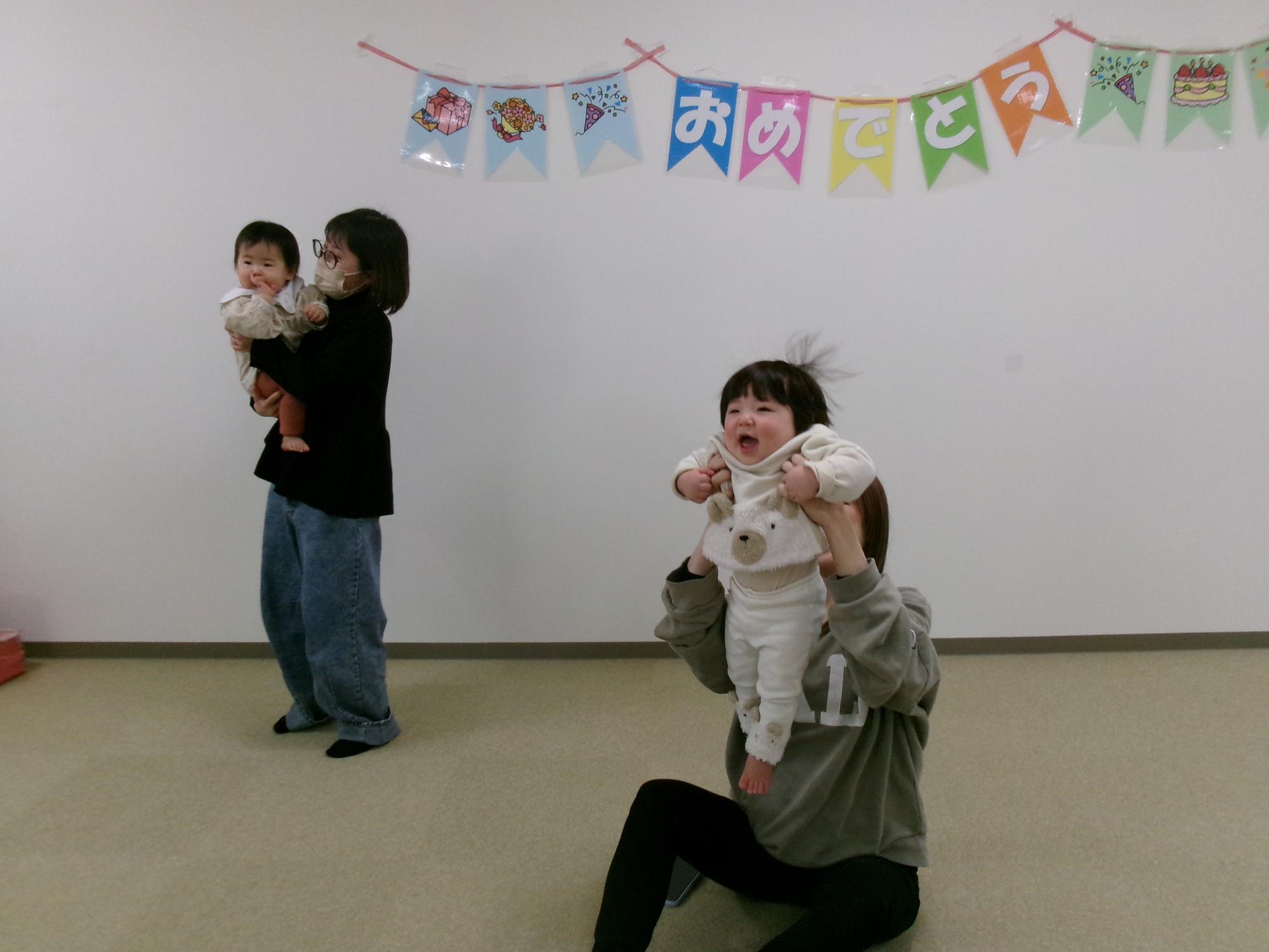 誕生会でお母さんが子どもを抱っこしている