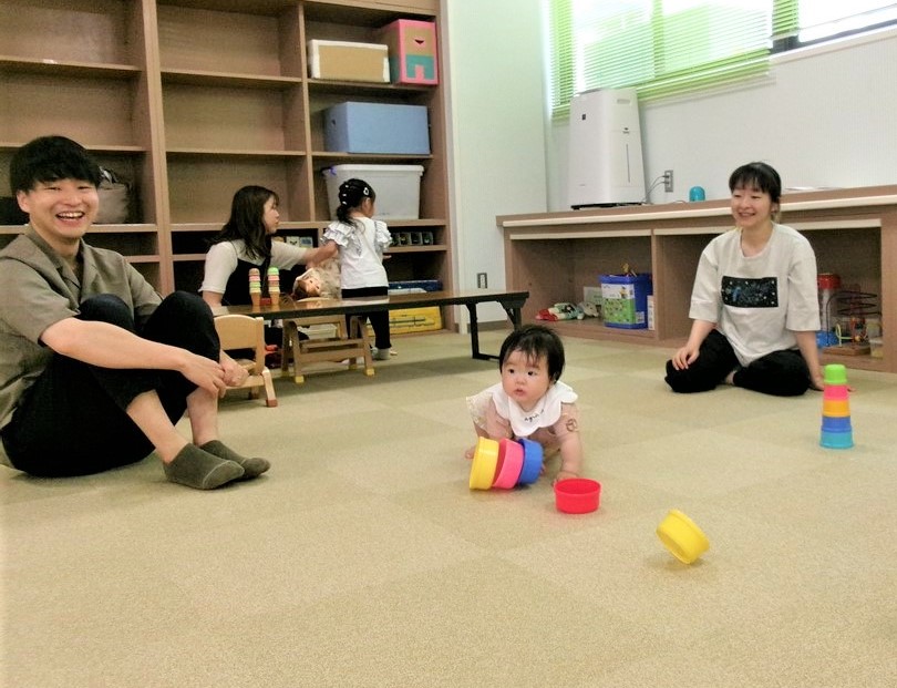 おもちゃで遊ぶ赤ちゃんを見守る父母
