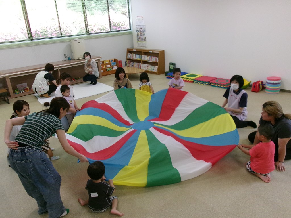 音楽に合わせてパラバルーンで遊ぶ親子