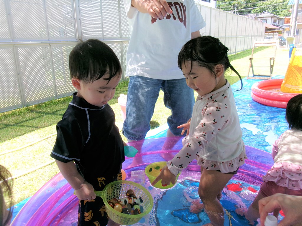 プールに入っておもちゃで遊ぶ子供たち