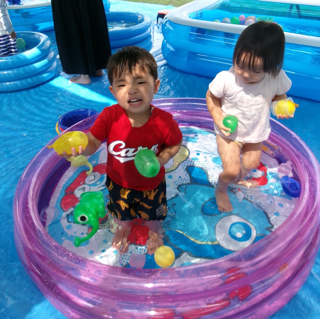 プールに入って水風船で遊ぶ子供の様子