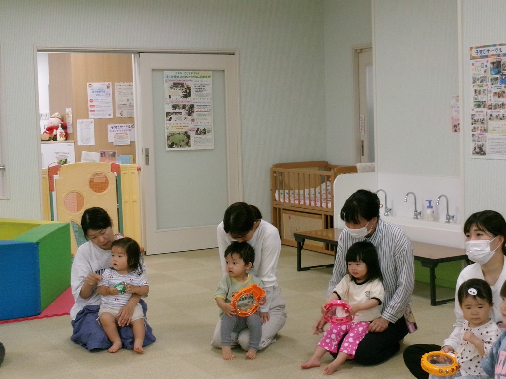 楽器を持って演奏する子どもを膝に座らせている様子