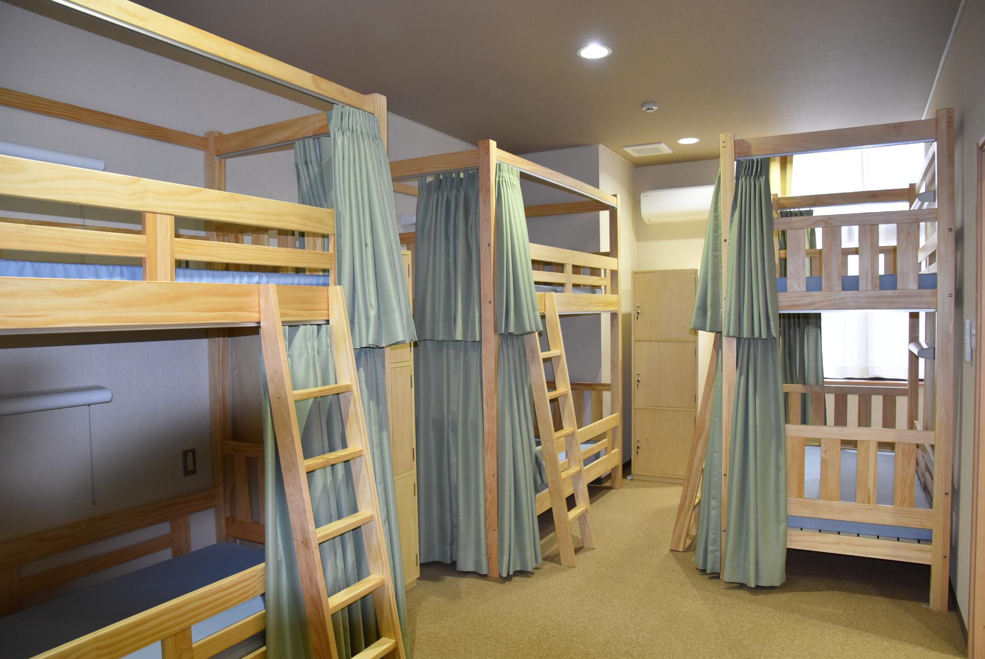 カーテンの付いた二段ベッドが3台設置されている部屋の写真