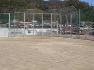 金網と網のフェンスがある土のグランドの写真