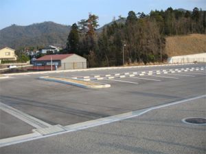 舗装され、車止めブロックがある駐車場の写真