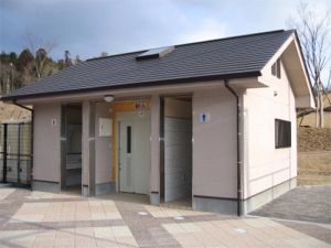 歩道の脇にある黒い屋根のトイレの写真