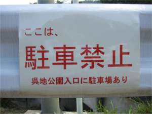 ガードレールに設置された「ここは、駐車禁止 呉地公園入口に駐車場あり」と書かれた張り紙の写真