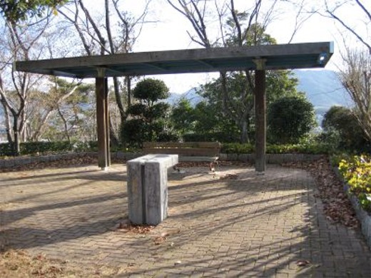 赤いレンガのタイルが敷き詰められた広場に水飲み場がある防主山緑地の写真