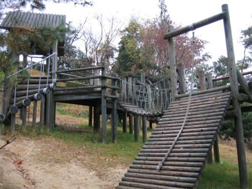ロープの設置された急な坂や橋などがある防主山緑地の木製複合遊具の写真