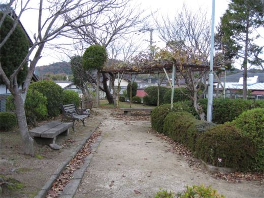 園内の歩道の脇に生垣とベンチが並んでいる東山公園の写真