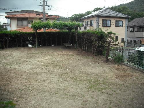 生垣に囲まれている土の地面がある石神公園の写真