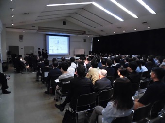 参加者が着席し、スクリーンで説明が行われている写真