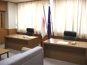 2つの席の間に日本国旗と紫の旗が立っている部屋の写真