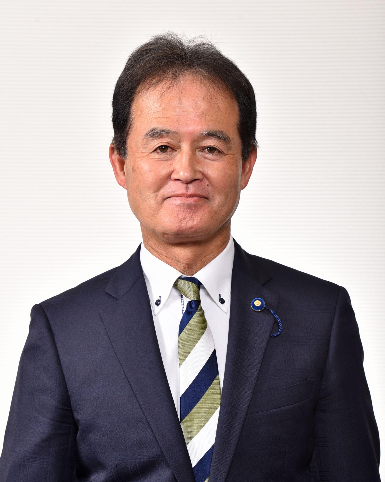 青・白・黄土色のストライプ模様をしたネクタイを付けたスーツ姿の男性の写真