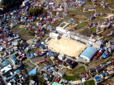 校舎、運動場、体育館と周辺の住宅地を一望できる学校全体の航空写真