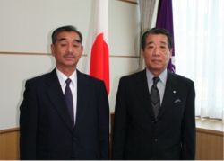 室内でスーツを着た2名の男性が正面を向いて撮影している写真